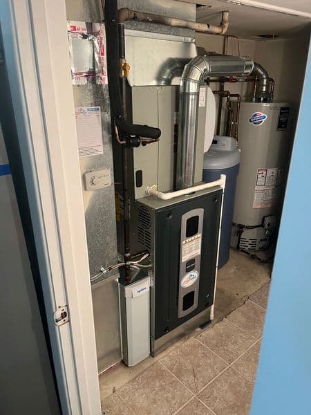 Home furnace and water heater in a utility room with gray tiled floor.
