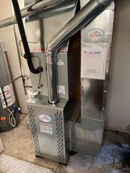 Modern furnace installation in a residential basement with visible ductwork and labels.