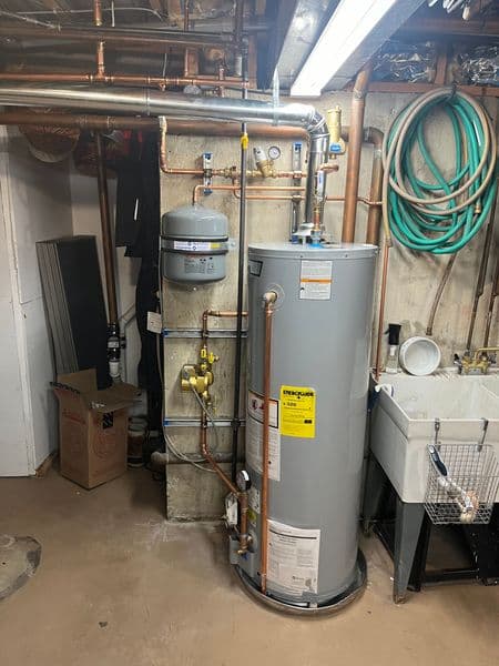 Newly installed hot water heater with copper piping in a basement setting.