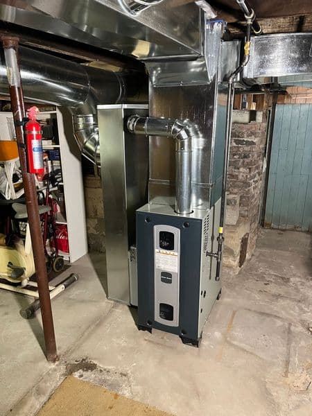Newly installed furnace in a basement with ventilation ducts and concrete flooring.