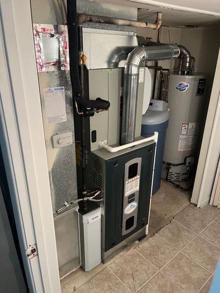 Furnace and water heater in a utility room with plumbing and ventilation details.