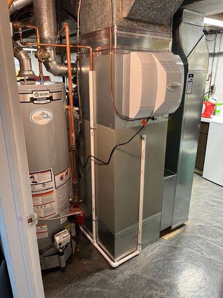 Home heating and hot water system with furnace, water heater, and ductwork in basement.